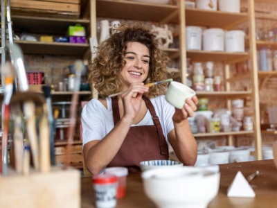 Craftsperson painting a bowl made of clay in art studio