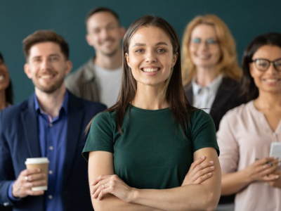 Close up headshot portrait of happy businesswoman hands crossed posture. Different age and ethnicity businesspeople standing behind of female company chief business. Leader of multi-ethnic team concept