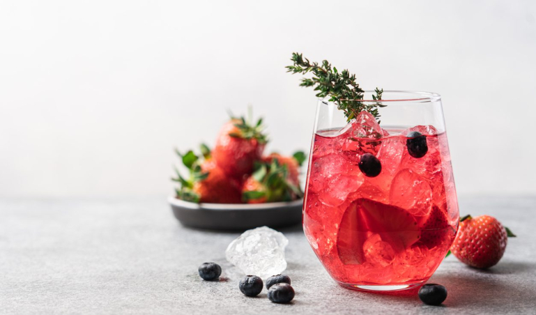 Pink drink with crushed ice and thyme. Strawberry and blueberry lemonade